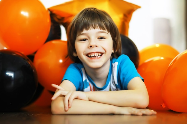 Portrait of a small child lying on the floor in a room decorated with balloons. Happy childhood concept.