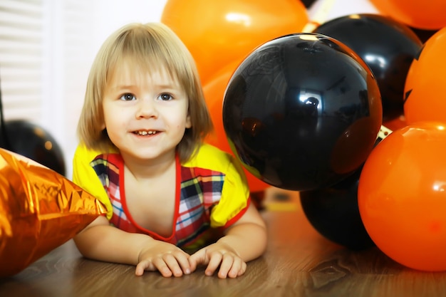 Portrait of a small child lying on the floor in a room decorated with balloons. Happy childhood concept.