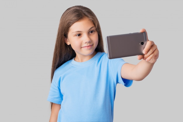 Portrait of a small girl taking selfie with a new smartphone