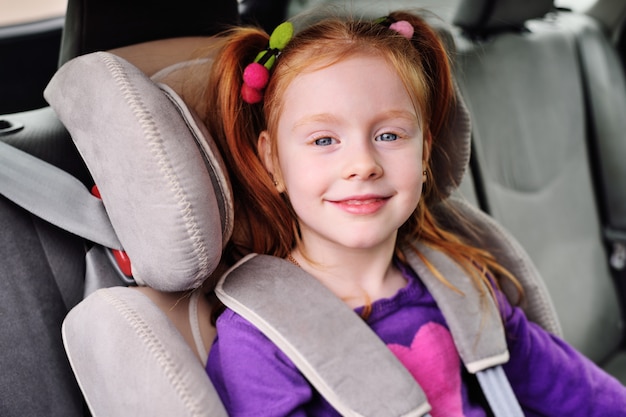 Portrait of a small red-haired girl in the car