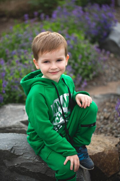 Portrait of a small smiling boy on the background of a blooming park