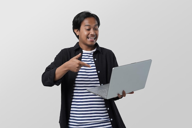 portrait of smart asian student holding a laptop in a hand with hand gesture, looking at camera