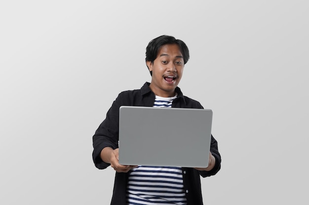 portrait of smart asian student holding a laptop in a hand with hand gesture and looking serious