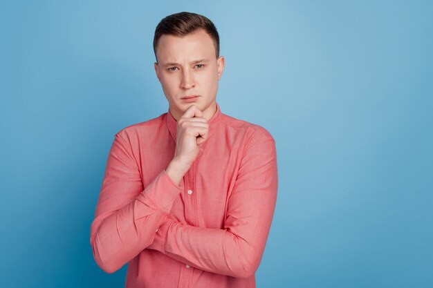 Portrait of smart celver guy hand chin look camera have thoughts on blue background