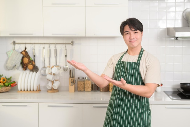 Ritratto di giovane uomo asiatico intelligente che sorride in cucina a casa