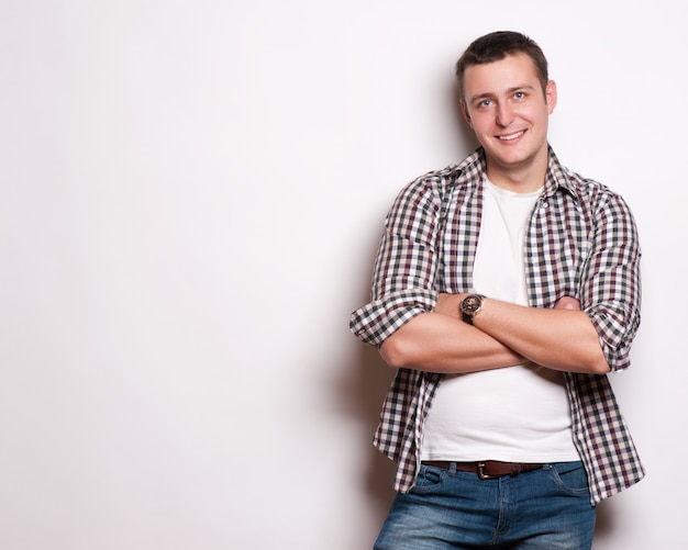 Portrait of a smart young man standing with arms crossed against gray background