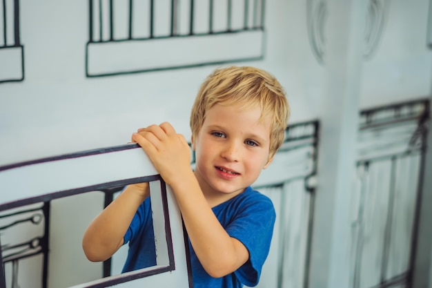 Portrait smile blue eyed freckled blond boy hide behind chair micro facial expression hand gesture Funny mischievous mood Happy childhood child behaviour education psychology relationship concept