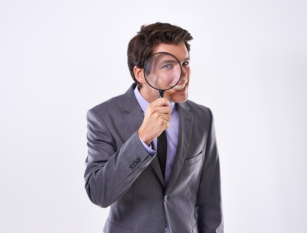 portrait smile and businessman with magnifying glass investigation and audit at company on white studio background face male employee and pi with compliance and fair trade evidence or information
