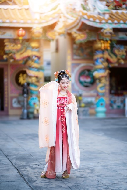 Портретная улыбка Милая маленькая азиатская девочка в китайских костюмах, украшенная для китайского новогоднего фестиваля, празднует культуру Китая в китайском храме. Общественные места в Таиланде