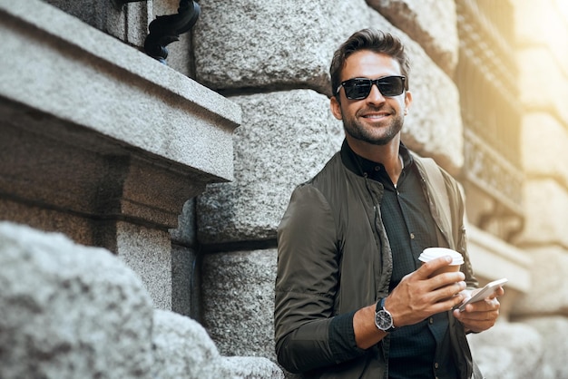 portrait smile and man with coffee outdoor and waiting for taxi sunglasses and communication with app fashion shades and person with smartphone for commuting street and confident in usa