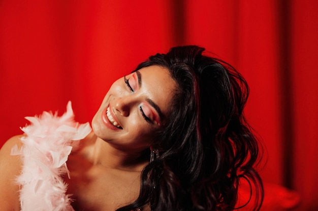 Portrait of smile sexy asian girl glam makeup in lingerie and feather boa among red shiny balloons