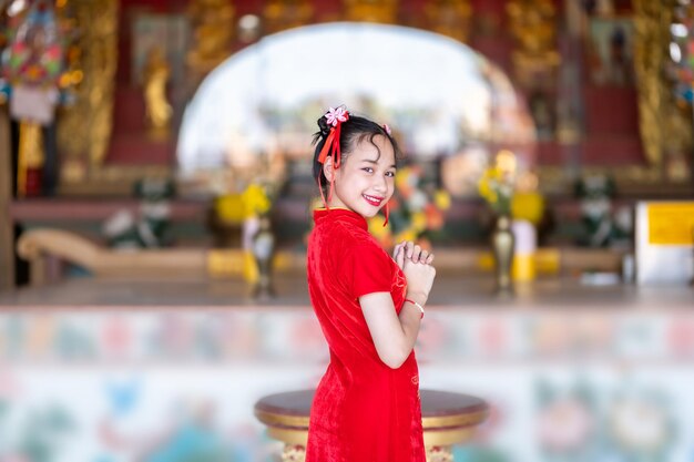 Portrait smiles Cute little Asian girl wearing red cheongsam dress traditional decoration for Chinese new year festival celebrate culture of china at Chinese shrine