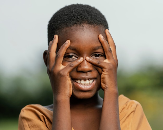 Photo portrait smiley african child holding hands on face