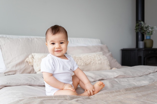 Portrait of a smiling 9monthold girl sitting on a bedxDxA