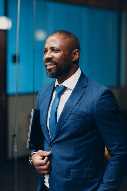 Photo portrait smiling african american businessman in blue suit in office