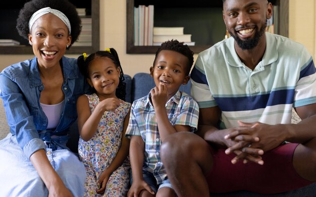 Photo portrait of smiling african american parents and children sitting on sofa in living room at home