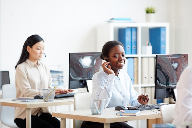 Portrait of smiling african-american woman wearing headset and talking to customer while working in support call center