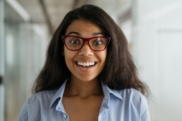 Portrait of smiling African American woman wearing stylish eyeglasses. Funny student with open mouth, education concept