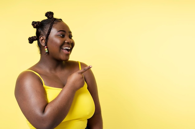Портрет улыбающейся африканской женщины с стильной прической, смотрящей в сторону, изолированной на желтом фоне