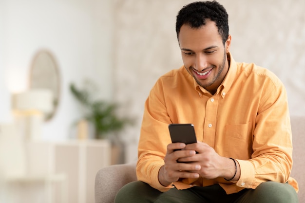 Portrait of smiling arab man using smartphone at home