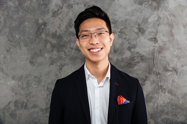 Photo portrait of a smiling asian man dressed in suit