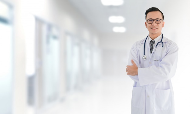 ぼやけた内部病院の前に立っているアジア医療男性医師を笑顔の肖像画