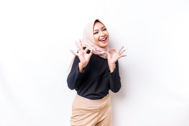 Portrait of a smiling Asian Muslim woman giving an OK hand gesture isolated over white background