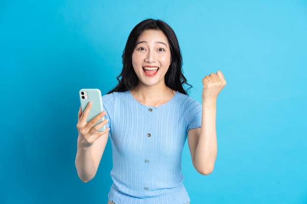 Portrait of smiling asian woman posing on blue background