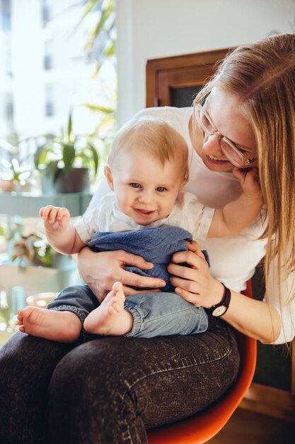 Portrait of smiling baby boy sitting on lap of his mother