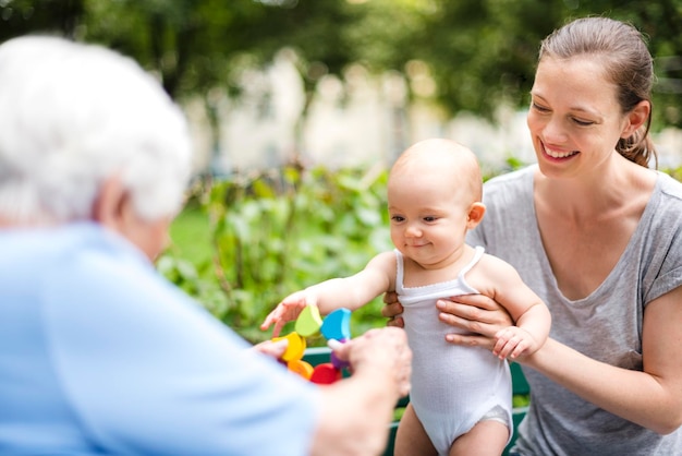 Portrait of smiling baby girl with grandmother and mother in a park