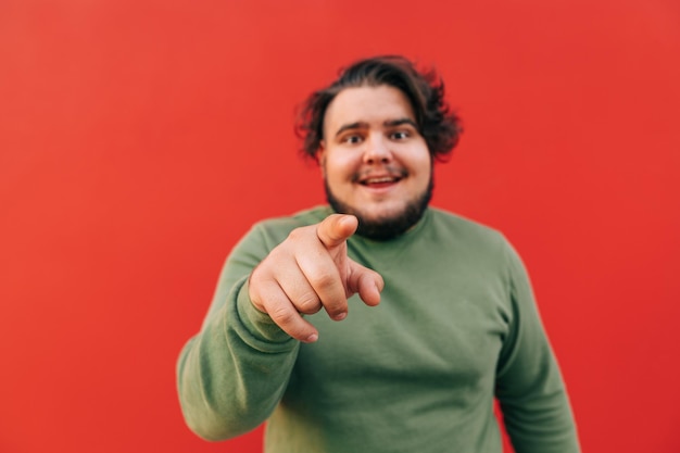 portrait of a smiling bearded hispanic man pointing at the camera with his finger looking funny