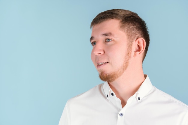 Portrait of a smiling bearded man looking away, close-up on a blue background