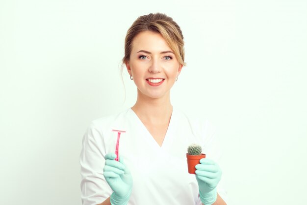 Portrait of smiling beautician woman holding pink razor and cactus.