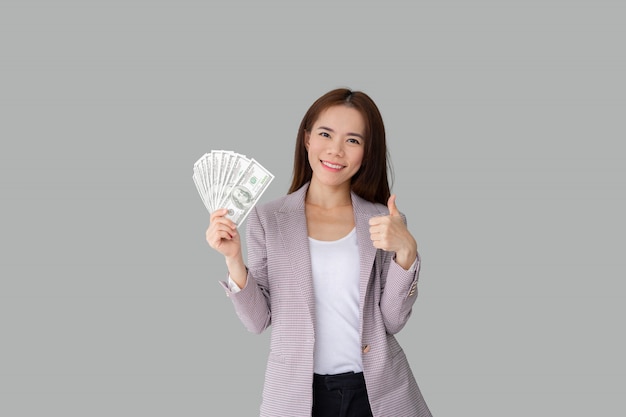 Portrait of smiling beautiful Asian woman holding lot of money banknotes