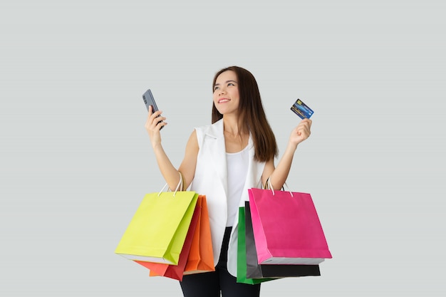 Portrait of smiling beautiful Asian woman holding shopping bags with credit card