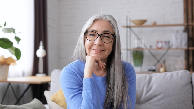 Portrait of smiling beautiful elderly gray-haired woman looking at camera.