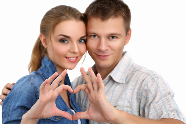 Portrait of smiling beautiful girl and her boyfriend making shape of heart by their hands isolated on white. Love concept.