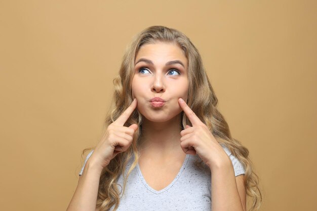 Photo portrait of smiling beautiful girl looking at camera over beige background.