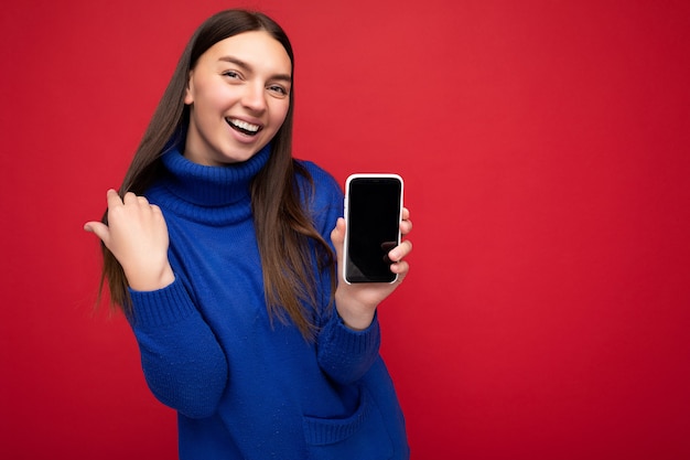 Portrait of smiling beautiful happy young brunette woman wearing casual blue sweater isolated over