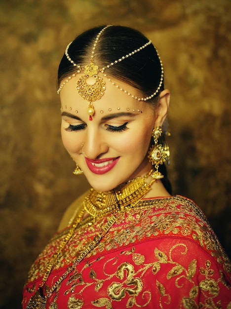 Portrait smiling of beautiful indian girl at home Young woman model with golden jewelry set