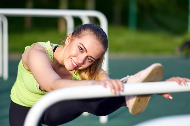 Portrait of smiling beautiful stretching danser or gymnast woman training in workout sports ground