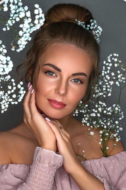 Portrait of a smiling beautiful sweet girl on a gray background with white flowers