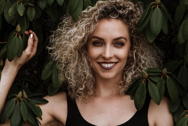 Foto ritratto di una bella donna sorridente in piedi vicino alle piante al parco