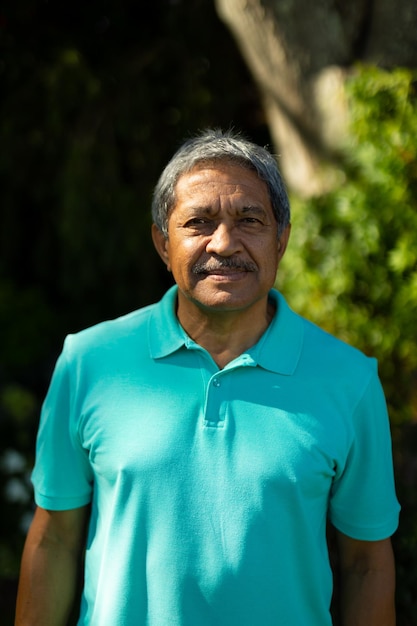 Photo portrait of smiling biracial senior man wearing blue t-shirt with gray hair standing in park