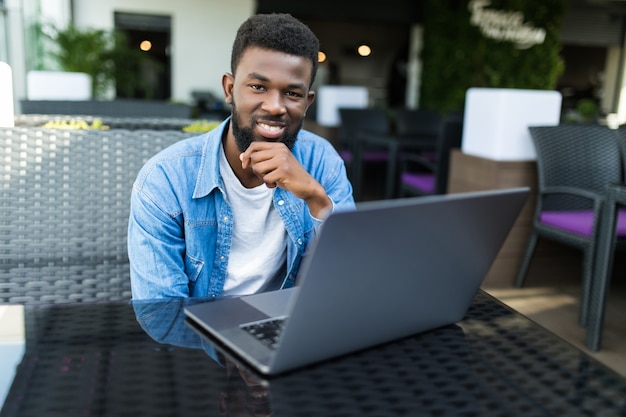 Portrait of a smiling black businessman with laptop at cafe