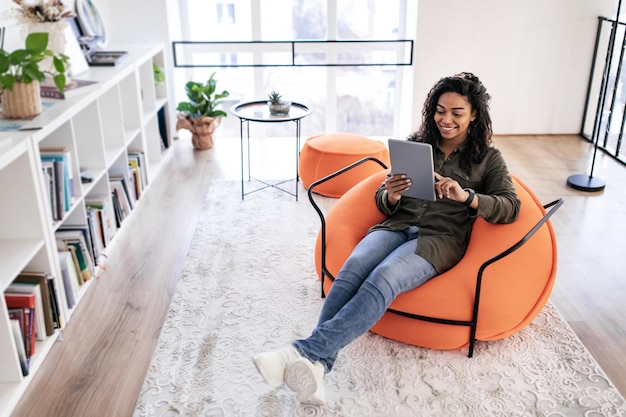 Portrait of smiling black lady using digital tablet at home