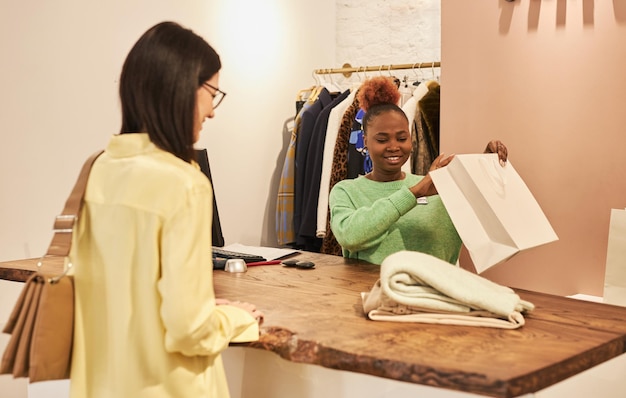 Portrait of smiling black woman serving female customer working in clothing boutique copy space