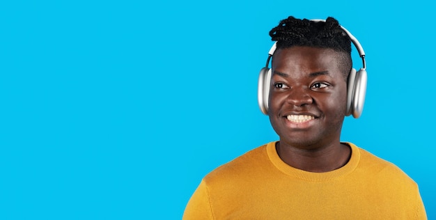 Portrait of smiling black young man listening music in wireless headphones