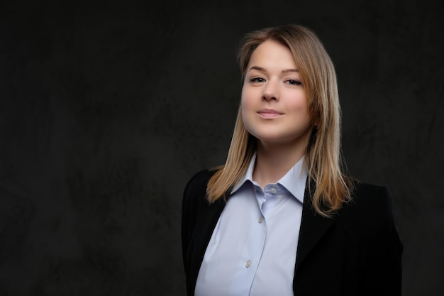 Portrait of a smiling blonde businesswoman formal dressed. Isolated on a dark textured background.