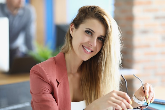 Ritratto di donna d'affari bionda sorridente sul posto di lavoro